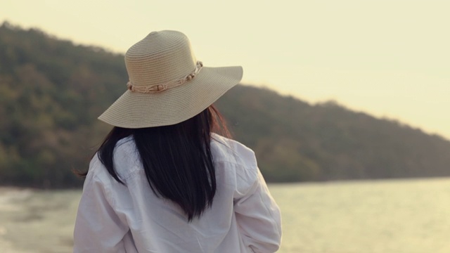 肖像快乐微笑的亚洲女人走在美丽的日落海滩上。生活方式旅游度假夏季概念。视频素材