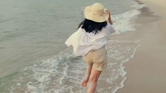 亚洲游客在海滩上跑步，在美丽的日落下享受海洋的乐趣。生活方式旅游度假夏季概念。视频素材