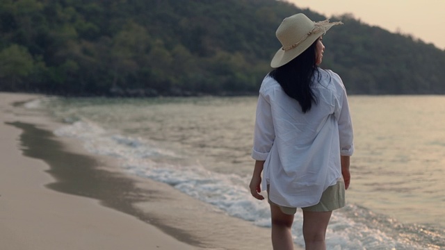 肖像快乐微笑的亚洲女性走在海滩美丽的日落。生活方式旅游度假夏季概念。视频素材