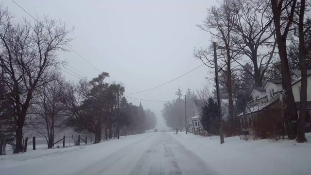 *反向运动*在白天将冬季暴风雪往后退。郊区公路上下着大雪。视频素材