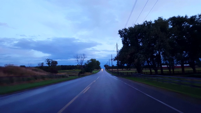 *倒车运动*在阴天下行驶乡村潮湿的道路。司机的观点POV后，黑暗的雨与水的街道倒退。视频素材