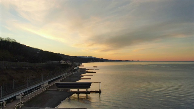 鸟瞰图飞过平静的海面朝向夕阳。美丽的金色日落在海上的全景视频素材