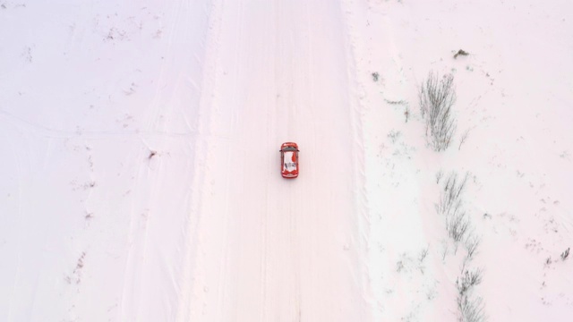 一辆汽车正行驶在冬日雪地上的乡间小路上。无人机鸟瞰图视频素材