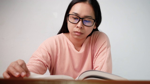 一名年轻女子在图书馆看书时翻动书页，手指在书页上移动。有选择性的重点。视频素材