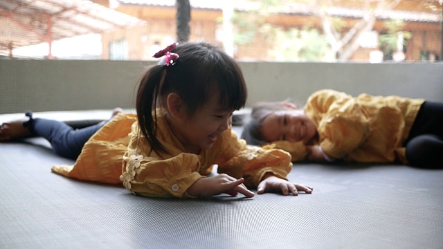 可爱的小女孩玩蹦床在操场上。幸福家庭和童年的概念。视频素材