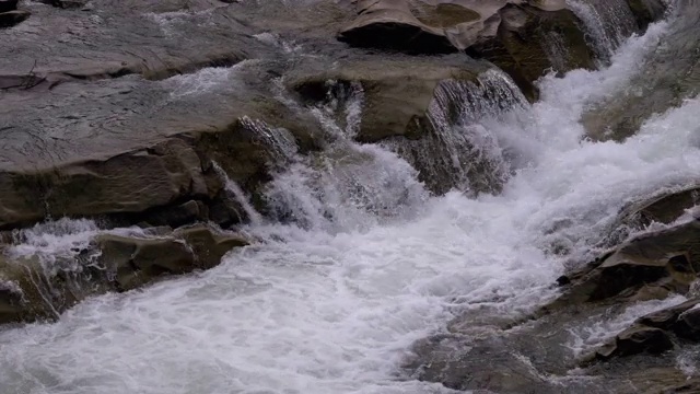 冬天的瀑布。湍急的水流从山溪和石滩与雪视频素材