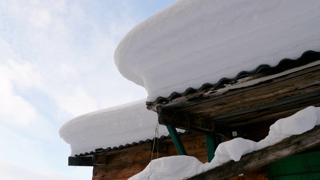 一个木制的乡村房屋屋顶的特写镜头覆盖着一层厚厚的蓬松的雪。俄罗斯西伯利亚的一个村庄，4K视频素材