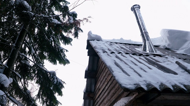 近距离拍摄的烟从烟囱在一个西伯利亚村庄的住宅建筑的屋顶。西伯利亚一户人家屋顶上的金属烟囱，4K视频素材