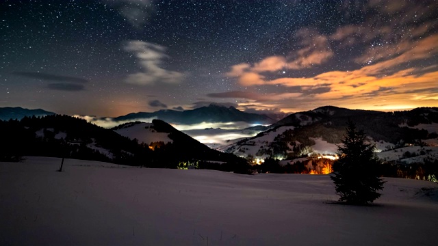 在乡村风景中，星空和彩云在冬季的山峦上快速移动视频素材