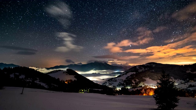 美丽的星空与星星和五彩缤纷的云在雪景时间流逝的冬季山脉的全景视频素材