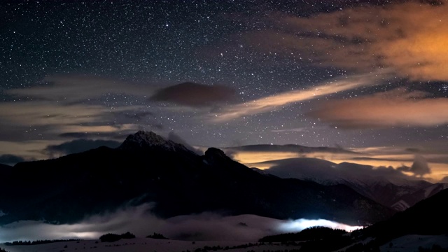 全景星空与星星和缤纷的云在冬季山与薄雾在山谷时间流逝视频素材