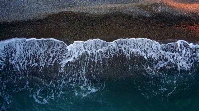 鸟瞰图美丽的海浪慢慢蔓延过海滩。美丽的波浪，在夕阳的金色时刻。无人机摄像头监视茴香视频素材