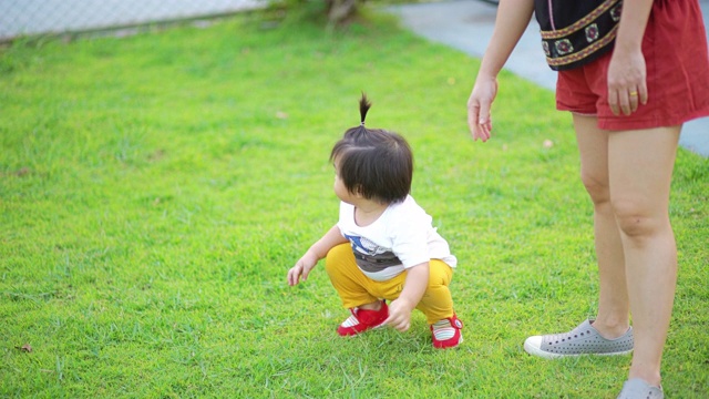 亚洲母亲抱着她的孩子从草地上视频素材