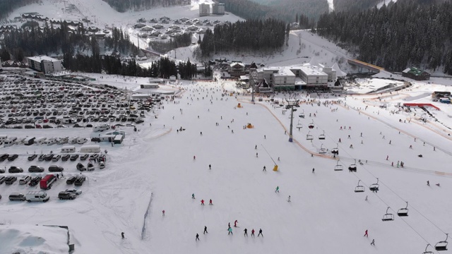 在滑雪胜地滑雪缆车附近滑雪斜坡上滑雪的许多人的鸟瞰图视频素材