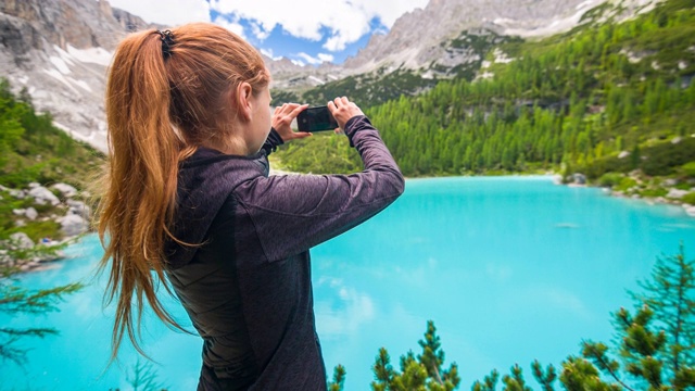 在晴朗的日子里，一名女性徒步旅行者在多洛米特的Sorapiss山湖用智能手机拍照视频素材