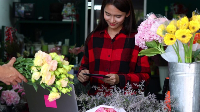 亚洲妇女花店小生意花店老板和她正在用她的电话和笔记本电脑为她的商店接受订单。视频素材