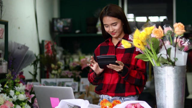 亚洲妇女花店小生意花店老板和她正在用她的电话和笔记本电脑为她的商店接受订单。视频素材