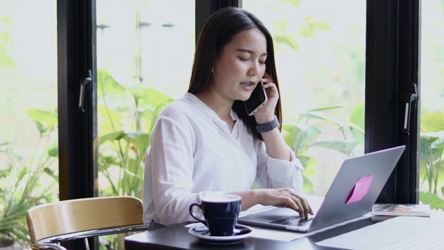 亚洲商业女性使用手机和触摸智能手机进行交流，女性使用笔记本电脑在咖啡店工作视频素材