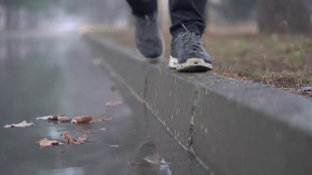 秋雨过后的落巷水坑，人们的脚踩在人行道上视频素材