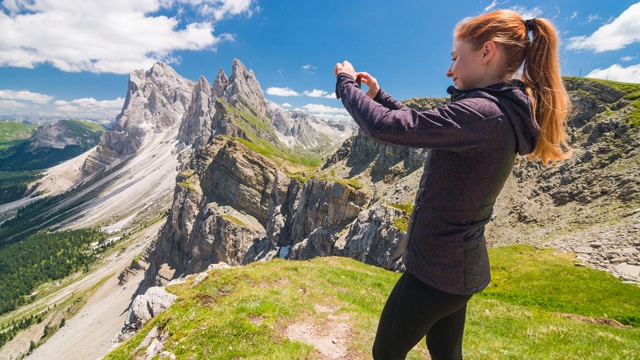 一名女性徒步旅行者在山顶用智能手机拍照视频素材