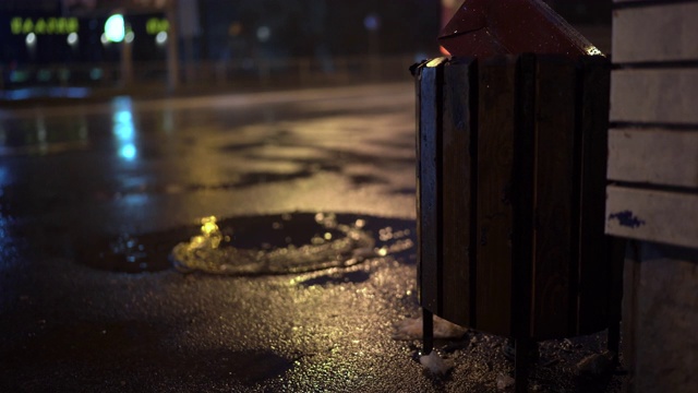 雨夜城市街道，街灯映照在雨后人行道上的水坑视频素材