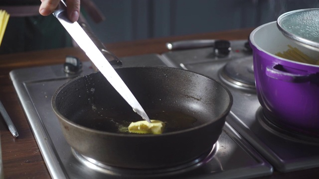 在厨房餐厅，厨师把一片黄油放在炉子上的热煎锅上。菜谱做饭。食品成分。烹饪美食。烹饪美食。准备吃的食物。美食烹饪。视频素材