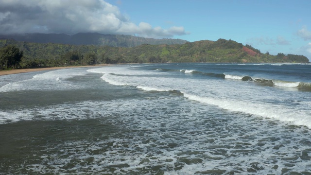 在夏威夷考艾岛的哈纳莱伊海滩上海浪和冲浪翻滚的侧面视图视频素材