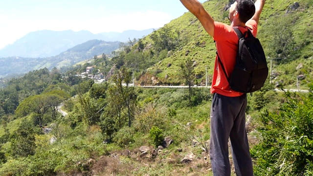 男性徒步旅行者背包到达山顶，伸出手臂。年轻的旅行者慢跑到峡谷的边缘，举起双手。游客欣赏美丽如画的风景。视频素材