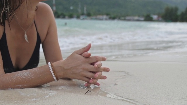 那个女孩躺在热带海滩的波浪中。视频素材