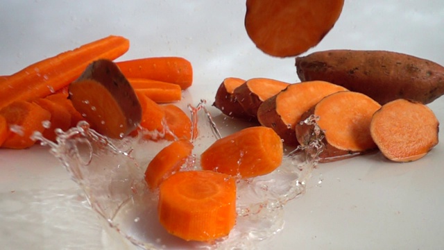 一片片的胡萝卜和巴塔掉进了水里。缓慢的运动。视频素材