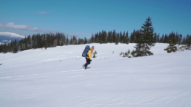 一个背着背包的男人冬天在山里旅行视频素材