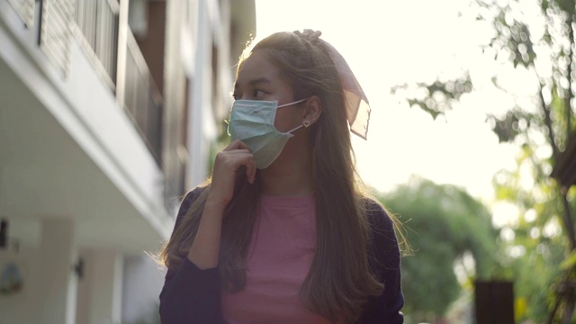 年轻的亚洲女子戴着药罩走路，学着看风景。视频素材