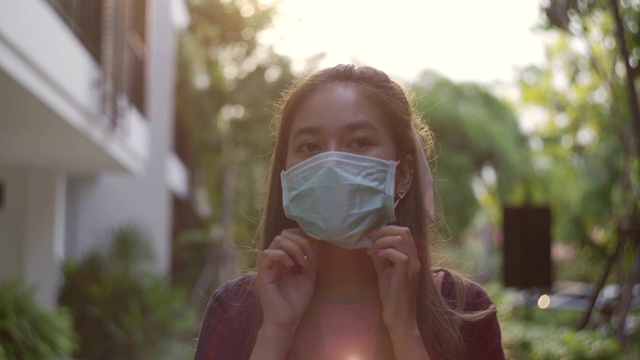 年轻的亚洲女子戴着药罩走路，学着看风景。视频素材