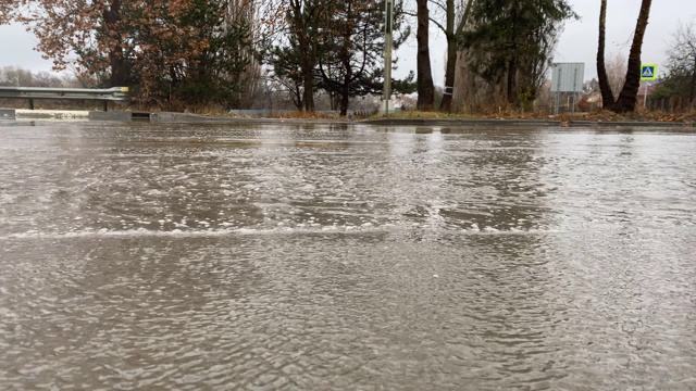 秋天的雨天，城市交通在潮湿的道路上行驶，汽车驶过一个车轮溅起水花的水坑。视频素材