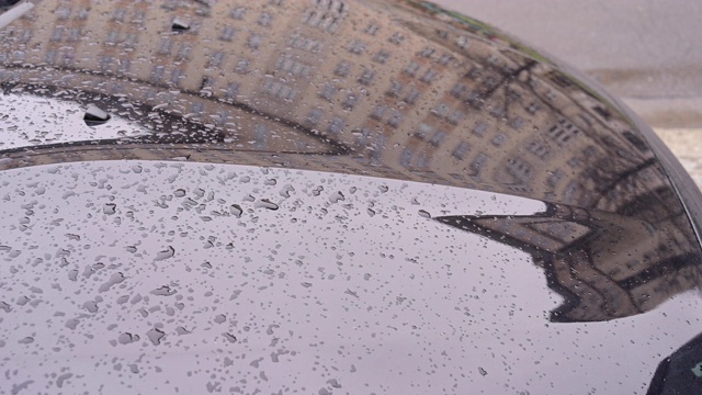 建筑和交通反映在停在街上的汽车的金属表面上。城市里的雨天。德国柏林。视频素材