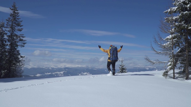 一个背着背包的男人冬天在山里旅行视频素材