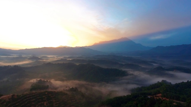 在婆罗洲沙巴州热带雨林中，以基纳巴卢山为背景的4k空中镜头美丽的日出视频素材