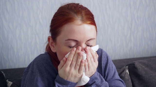 生病的女人在家里打喷嚏时裹着纸围巾。视频素材