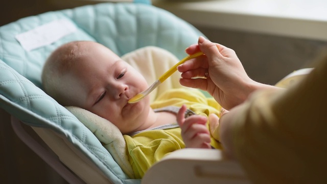 母亲用勺子喂婴儿。妈妈给孩子食物视频素材