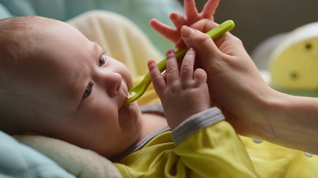 母亲用勺子喂婴儿。妈妈给孩子食物视频素材