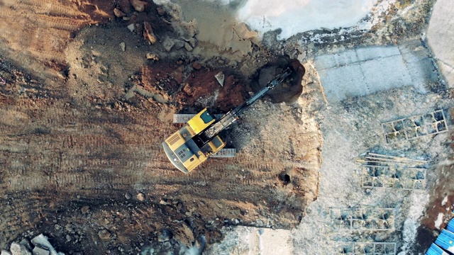 俯视图挖掘机从地面建筑物的洞中抓取泥土，施工过程。视频素材