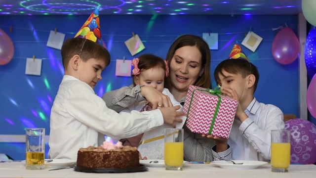 孩子们祝贺一岁的小女孩生日快乐，并赠送礼物视频素材