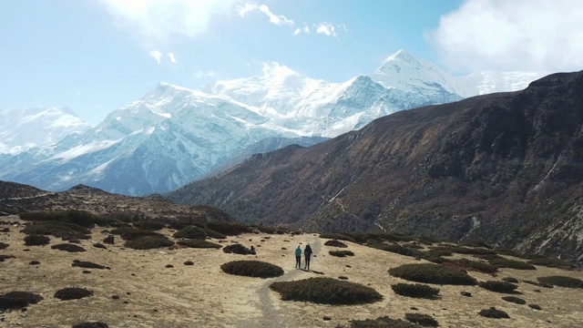 一对夫妇在尼泊尔喜马拉雅山Annapurna马戏团徒步旅行的Manang山谷，在Annapurna链和Gangapurna的景色。干燥和荒凉的景观。白雪覆盖着高耸的山峰。视频素材