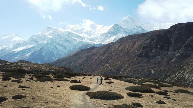 一对夫妇在尼泊尔喜马拉雅山Annapurna马戏团徒步旅行的Manang山谷，在Annapurna链和Gangapurna的景色。干燥和荒凉的景观。白雪覆盖着高耸的山峰。视频素材