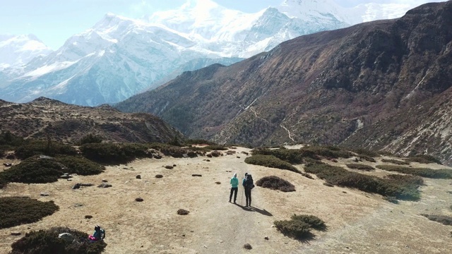 一对夫妇在尼泊尔喜马拉雅山Annapurna马戏团徒步旅行的Manang山谷，在Annapurna链和Gangapurna的景色。干燥和荒凉的景观。白雪覆盖着高耸的山峰。视频素材