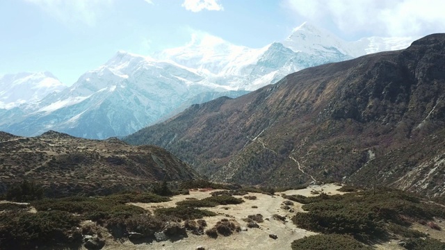 一对夫妇在尼泊尔喜马拉雅山Annapurna马戏团徒步旅行的Manang山谷，在Annapurna链和Gangapurna的景色。干燥和荒凉的景观。白雪覆盖着高耸的山峰。视频素材