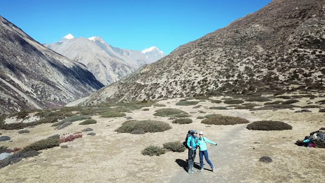 一对夫妇在尼泊尔喜马拉雅山Annapurna马戏团徒步旅行的Manang山谷，在Annapurna链和Gangapurna的景色。干燥和荒凉的景观。白雪覆盖着高耸的山峰。视频素材