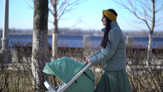 一个女人在春天里推着婴儿车穿过公园视频素材