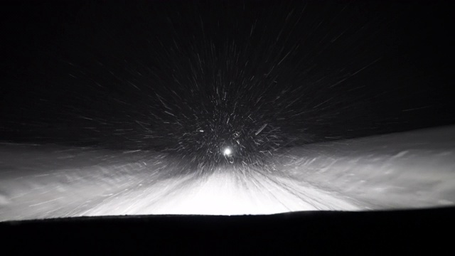 夜晚驾驶通过暴风雪的冬季风暴挡风玻璃Pov雪花在前灯视频素材