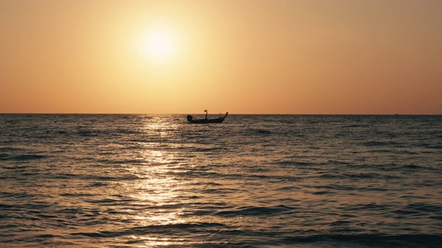 一艘泰国船在夕阳西下时在泰国海上的波浪上摇摆视频素材